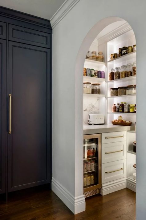 Essentials are kept organized while on display in this walk-in kitchen pantry. An open arched doorway adds architectural interest to the space, which also includes a small wine refrigerator and a countertop with room for small appliances. Pantry Closet Remodel, Butler Pantry Decor, Fireplace Detail, Pantry Renovation, Pantry Closet Design, Arched Doorway, Home Pantry, New Build Ideas, Home Must Haves