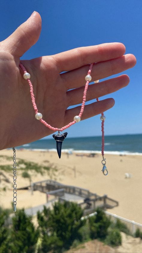 This is the  wonderful Pink Tooth necklace. The pink glass beads and faux pearls help this necklace beautiful. The fossilized shark tooth at the center ties the necklace together giving it natural yet fashionable look. Shark teeth have been worn by first humans to walk this earth. Shark teeth are said to give protection and safety while wearing them. Do yourself a favor and get your very own piece of paradise! Every necklace is handmade with love and care🤍 How To Make Shark Tooth Necklace, Beaded Shark Tooth Necklace, Shark Tooth Necklace Aesthetic, Shark Teeth Crafts, Tiktok Jewelry, Shark Teeth Jewelry, Beachy Necklace, Pink Beaded Necklace, Beachy Jewelry