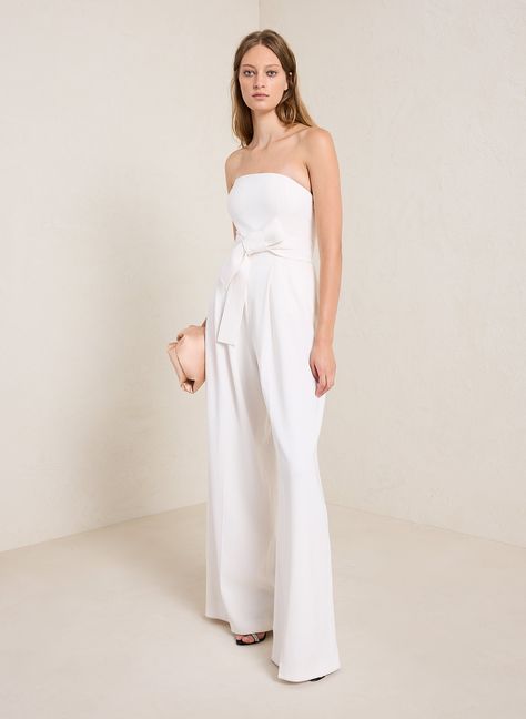 The Elsie Jumpsuit is impeccably cut from refined winter white fabric. This strapless silhouette features pleated wide legs with pockets and a detachable belt to highlight the waist. We recommend to size up one from your typical size. This style runs small. Shop Jumpsuits Styling Tip: Pair with strappy stilettos and a rhinestone shoulder bag for a nostalgic bridal look. Jumpsuit Styling, Satin Jumpsuit, Wedding Jumpsuit, Strappy Stilettos, Vegan Leather Jacket, Strapless Jumpsuit, Bridal Look, White Jumpsuit, Reception Dress