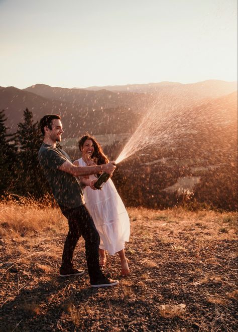 Popping champagne on top of an Oregon mountain. Champagne Anniversary Photo, Popping Champagne Couple Pictures, Couple Photoshoot With Champagne, Engagement Photos Popping Champagne, Engagement Photoshoot Ideas With Champagne, Engagment Photo Champagne, Engagement Photo With Champagne, Engagement Photo Poses Champagne, Fun Engagement Photos Champagne