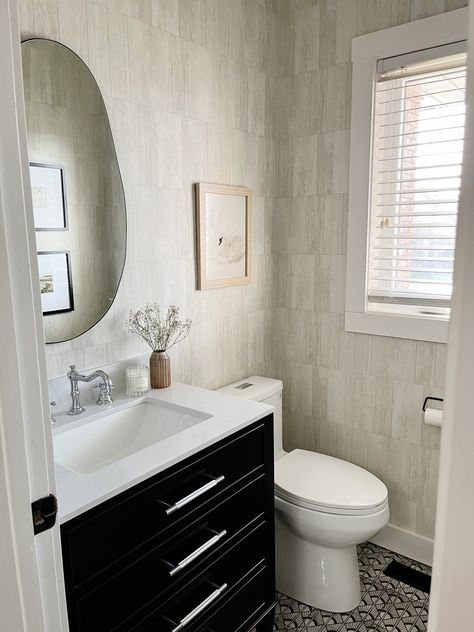 A powder room always gives off a first impression to your guests since it is almost always used by them! We have been wanting to completely renovate our powder room since we moved into this home. It had a very unique floor to ceiling mirror, which made for a great joke when guests used the restroom, and had an outdated flooring and vanity. In this post, we’ll go through each step we took to transform and DIY our powder room, including demo & removal of a builder-grade mirror, tiling, a Wallpaper Vanity, Floor To Ceiling Mirror, Ceiling Mirror, Full Wall Mirror, Black Door Knobs, Black Grout, Toilet Door, Builder Grade, Black Vanity