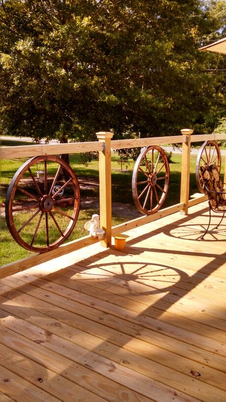 My wagon wheel railing I added to my new deck Diy Deck Railing Ideas, Diy Deck Railing, Wagon Wheel Decor, Wood Deck Railing, Deck Diy, Deck Railing Ideas, Deck Railing Design, Laying Decking, Wagon Wheels