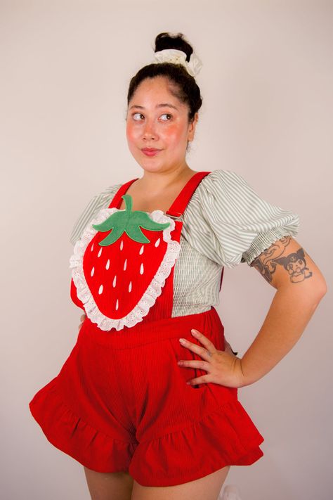 Dive into the charm of our vibrant red Strawberry Romper, adorned with a luscious embroidered strawberry and delicate white lace trim. Complete with matching back pockets, this romper is your go-to choice for a delightful trip to the strawberry farm during this perfect season. Experience nature's candy firsthand—juicy and ripe, just waiting for you to pick and enjoy! Details: Corduroy Embroidered strawberries Ruffle shorts Side pockets and bib pocket Elastic waistband in back Model is wearing si Strawberry Inspired Outfit, Fruity Outfits, Watermelon Clothes, Strawberry Overalls, Fruit Clothes, Embroidered Strawberries, Strawberry Romper, Embroidered Strawberry, Strawberry Farm