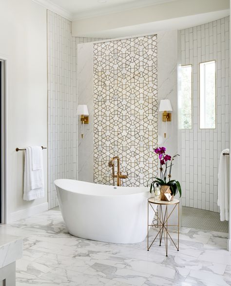 This luxurious master bath features a freestanding tub, a shell chandelier in the 22' high cupola, a striking gold and marble mosaic accent wall behind the tub, a curved walk in shower, and custom his and hers vanities with a large seated vanity area. Bath Tub, Master Bath, Accent Wall, Bath, Shower, Wall, White, Design