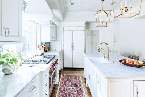 A red runner sits on a rustic wood floor in front of a Wolf range flanked by white kitchen cabinets adorned by polished nickel pulls and a honed white marble countertop. Hood In Front Of Window, Oak Floor Kitchen, Katie Davis Design, Rustic Countertops, Katie Davis, Light Oak Floors, Rustic Wood Floors, Style Me Pretty Living, Cheap Flooring