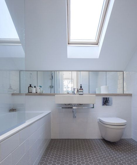 Wall-mounted sinks and toilet, skylight, cool floor, glass door over shower/tub combo.   Roof extension to east london flat by Poulsom Middlehurst Ceiling Window Bathroom, Clad Extension, Loft Ensuite, Attic Flat, Windows Bathroom, Gabled Roof, Attic Makeover, Sloping Roof, Roof Lights