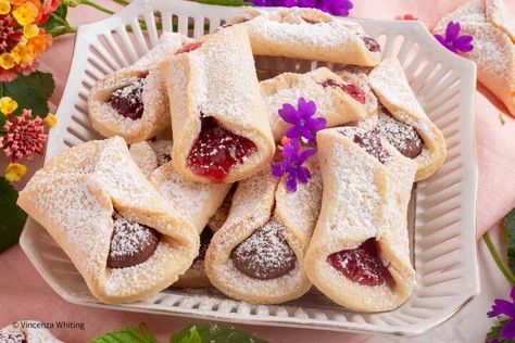 Pizzicati (Italian pinch cookies), are delicious buttery cookies filled with jam, gently pinched in the center, and then finished off with a dusting of powdered sugar. Better than any bakery cookies, these delicate Italian shortbread cookies are tender and lightly sweet with just a hint of citrus in the dough.  Pinch cookies are often part of an Easter, Christmas or wedding dessert tray, along with other Italian favorites such as Sicilian Pignoli Cookies, Cuccidati, Chocolate Spice C… Pinch Cookies, Hummingbird Cake Recipes, Sesame Cookies, Italian Bakery, Filled Cookies, Dessert Tray, Buttery Cookies, Italian Cookies, Fruit Jam