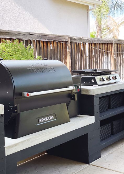 Black Traeger Grill and a stove top placed on a black and white custom countertop Traeger Grill Outdoor Kitchen, Outdoor Kitchen For Traeger Grills, Back Patio Grill Ideas, Blackstone And Smoker Outdoor Kitchen, Black Stone Grill Station, Outdoor Charcoal Grill Station, Diy Outdoor Traeger Grill Station, Outdoor Kitchen With Traeger Grill And Blackstone, Traeger Grill Setup