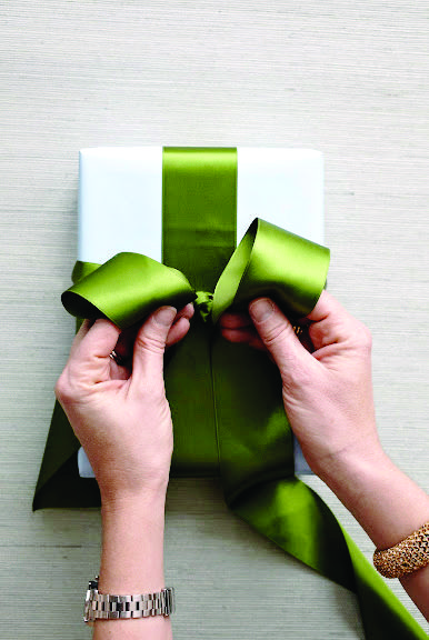 Holiday Gift Wrapping: How To Tie The Perfect Bow | Chatelaine Tie A Bow On A Present, How To Tie A Bow On A Package, How To Do A Bow With Ribbon On A Present, Easy Gift Bows With Ribbon, Satin Ribbon Bow Gift Wrapping, How To Tie Satin Ribbon Bow, How To Wrap A Present With Ribbon, Tying Gift Bows, How To Tie Gift Bow