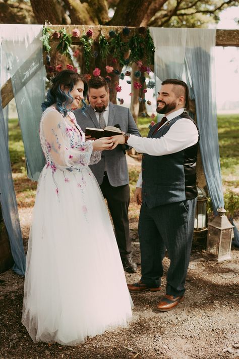 A magical DnD-themed wedding! 🌸🎲 From the bride putting on the groom's ring to their first kiss and celebrating up the aisle, these moments are pure enchantment. The floral dress, the wooden arch with blue ombré draping, and the whimsical flower backdrop add a touch of fantasy to this special day. Warhammer Wedding, Dnd Wedding Ideas, D&d Wedding, Dnd Wedding, Gamer Wedding, Hand Fasting, Dragon Wedding, Nerdy Wedding, Whimsical Flower