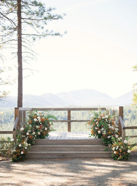 Orange and white flower arrangements on both side of a wooden staircase leading up to The Lookout spot at Suncadia Resort in Cle Elum, Washington. Suncadia Wedding, Deck Wedding Ceremony, Mountain Wedding Arch Outdoor Ceremony, Ground Meadow Wedding Ceremony, Wedding Ceremony Mountain Backdrop, Sunrise Amphitheater Wedding, Wedding Ceremony Mountain View, Romantic Wedding Vows, Summer Wedding Venues