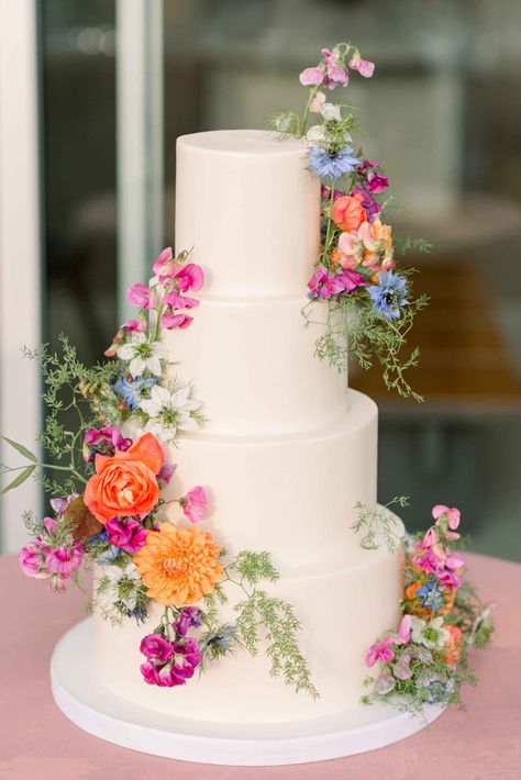 The tiered wedding cake with flowers in bright blue, coral, pink and orange with delicate greenery. Wedding Dessert Table Colorful, Ethereal Spring Wedding, Italian Vineyard Wedding Aesthetic, Wedding Cakes With Wild Flowers, Spring Floral Wedding Cake, 3 Tier Wedding Cake With Flowers, Tiered Wedding Cake With Flowers, Pink Floral Wedding Cake, Spring Wedding Cakes