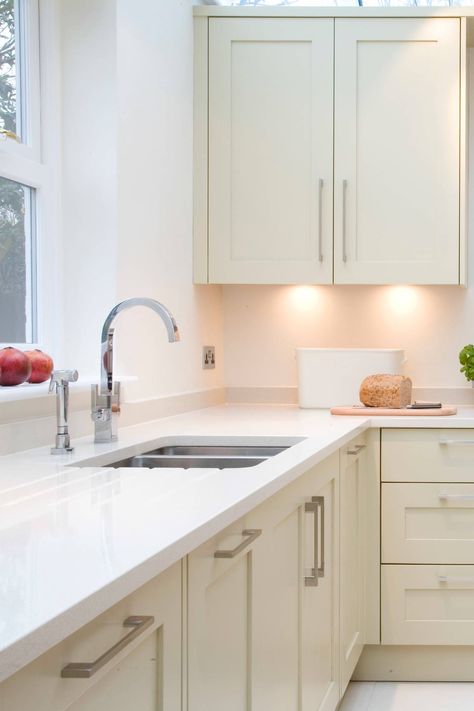 Simple and clean lines are used for this contemporary cream kitchen. #cabinetcolors #cabinetsideas #moderncabinets #creamcabinets #creamcabinetry #creamcupboard #creamshaker #shakercabinets #whitequartz #quartzcountertops #quartztops #whitecountertops #quartzcountertops #beigetiles #beigeporcelain #beigefloor #beigeceramic #beigeflooring #brashedhandles #lightwoodcabinets #lightwoodcabinetry #lightwoodcupboard #pendantlight #recesslight #sink #whitewallpaint #undercabinetlights #kitchendesign Kitchen Cabinets With White Countertops, Cabinets With White Countertops, Cream And White Kitchen, Light Wood Kitchen Cabinets, Light Wood Kitchen, Modern Rustic Kitchen, Cream Kitchen Cabinets, Taupe Kitchen, Light Wood Kitchens