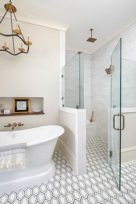 Floor level shower with white, gray and black geometric floor tiles featuring a zero-entry glass-enclosed walk-in shower with a brass kit and staggered marble wall tiles. Pike Properties, Bathroom Facelift, Geometric Floor Tiles, Condo Bathroom, Geometric Floor, Remodel Inspiration, Master Bath Remodel, Shower Tile Designs, Tile Shower Ideas