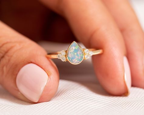 "Valentine Day Sale! 14k Gold Opal Engagement Ring/Pear Shaped Ring/Teardrop Opal Diamond Ring/Natural Ethiopian Opal/Promise Gift/Proposal ★ ★ ★ ★ CUSTOM/DUTY-FREE SHIPPING WORLDWIDE, BUYERS DON'T HAVE TO PAY ANY CUSTOM FEES WHILE IMPORTING ★ ★ ★ ★ Details Made to order Material: 14k/18k Gold Color Options: Yellow Gold, White Gold, Rose Gold, ★ Center Stone: Opal, Pear Size: 5 x 7 mm Approx Weight (Ct): 0.69 ★ Accent Stones: Diamond Round Size: 1.5 mm * 6 No.s Approx Weight (Ct): 0.084 ★ 100% N Engagement Ring Teardrop, Cluster Wedding Band, Gold Opal Engagement Ring, Opal Promise Ring, Ring Teardrop, Opal Diamond Ring, Pear Shaped Ring, Pear Shaped Engagement Rings, Bezel Set Ring