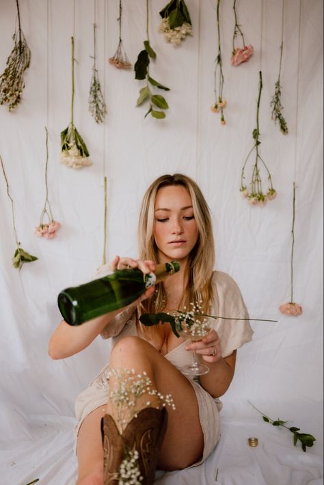 Girl pouring sparking grape juice into a wine glass while flowers are everywhere Self Portrait Photography Backdrop, Photo Shoot With Sheet Backdrop, Easter Photography Ideas Indoor, Floral Ladder Photoshoot, Backdrop Setup Ideas, Simple Backdrop Photoshoot, Floral Background Photoshoot, Floral Birthday Photoshoot Ideas, Indoor Spring Photoshoot