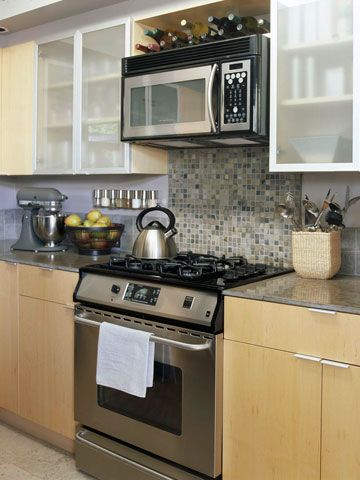 Tiled Backsplash- Create an eye-catching focal point in a small kitchen without spending a lot by lining the wall behind the range with decorative tile. Most 1x1-inch tiles come already attached to a 12x12 mesh sheets, making installation and custom-fitting easier. Slab cabinetry doors on base units and frosted glass doors above contribute to the clean, and streamlined look of this small kitchen. Microwave Above Stove, Small Kitchen Tiles, Stove Backsplash, Microwave In Kitchen, Small Kitchen Decor, Coffee Wine, Interior Modern, Kitchen Tiles Backsplash, Kitchen Redo