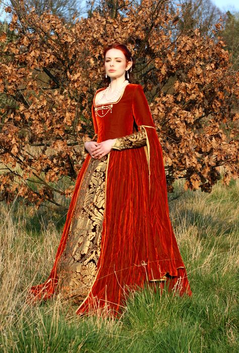 This beautiful luxurious gown is the perfect addition to a Tudor or Medieval themed wedding. It is made from thick pile super soft russet velvet with a rich brown velvet underskirt that features a gold printed design. The long sleeves are lined with gold satin, while the undersleeve matches the underskirt panel and the whole gown is luxuriously trimmed with white and gold plaited braid. It is finished off with a gold and pearl bodice brooch. Fest Outfits, Fantasy Dresses, Velvet Gown, Medieval Costume, Old Dresses, Medieval Dress, Medieval Clothing, Medieval Fashion, Historical Costume