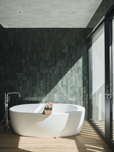 The walls and ceiling of the primary bathroom are clad in Bedrosians ceramic tile. #dwell #phoenix #moderndesign #hometours #tub Modern Desert Home, Glossy Ceramic Tile, Creative Tile, Light Hardwood, Modern Desert, Light Hardwood Floors, Desert Homes, Green Tile, Ceramic Wall Tiles