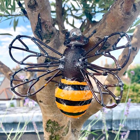 Designed exclusively by London Garden Trading, our charming metal Honey Bee garden sculpture decoration is perfect to accessorise your garden. Our lovely giant honey bee sculpture has been created and painted by hand by a fairtrade company in Africa using recycled steel from oil drums and car parts. It looks adorable sitting in a tree in your garden or perched on a fence or table. This recycled garden decoration is designed to reflect the rustic nature of the materials used to create it and ever Metal Bee Sculpture Wall Art, Bee Sculpture, Honey Bee Garden, Bumble Bee Decorations, Scrap Recycling, Cutlery Art, Poppy Garden, Sitting In A Tree, Welding Art Projects