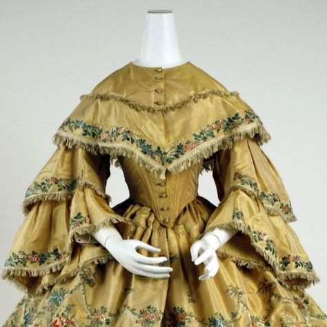 Fashion History Timeline on Instagram: "This 1859 ensemble has a gold, two-tiered skirt and pagoda-sleeves, both of which are edged in a red, green, and peach floral brocade pattern. This silk day dress has a round-necked bodice with a frayed v-shaped seam above the bust and frayed edges. The edges of the tiers of the pagoda sleeves are also frayed, as are the two tiers of the large, round cage crinoline-shaped skirt. The bust-level tier of the bodice, alongside both tiers of the pagoda sleeves, have an approximately two-inch-wide green and red floral brocade pattern, while both tiers of the skirt are adorned with a pattern similar to that of the bodice and sleeves. But the patterning also creates the illusion of additional tiers on the skirt by depicting what appear to be frayed, scallope Pagoda Sleeve, Fashion History Timeline, Brocade Pattern, History Timeline, Dress Hats, Green And Red, Architecture Fashion, Day Dress, Sleeves Pattern