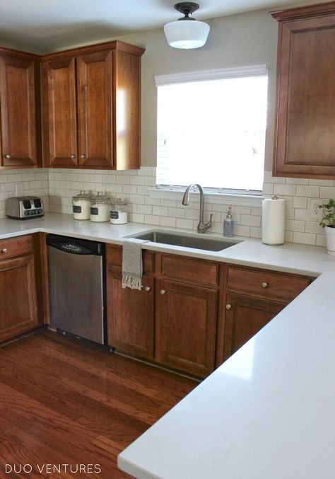 Brown Cubbards Kitchen, White Counter Brown Cabinets, Apartment Kitchen Brown Cabinets, White Countertops Brown Cabinets, Brown Cabinets With White Backsplash, Brown Kitchen With White Counter, White Backsplash Brown Cabinets, Brown Cabinets Kitchen White Counter, White Kitchen With Brown Cabinets