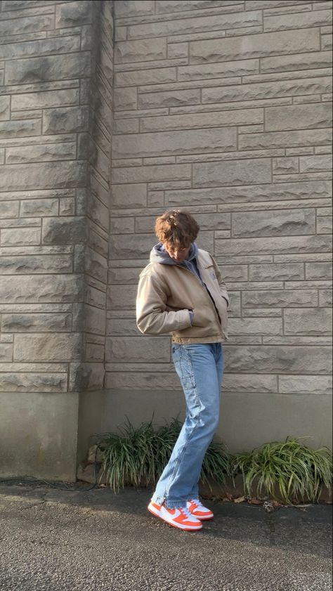 A simple winter or fall outfit. The outfit features a gray hoodie that is layered with a vintage, tan, sun faded carhartt Detroit jacket. The pants are faded blue carpenter jeans from Hydraulic. These jeans have a slight flare at the bottom. Lastly, the shoes are the Nike Dunk High sneakers in the Syracuse colorway, which is orange and white. Dunk Syracuse Outfit, Nike Dunks Outfit Men, E Boy Style, Nike Dunk Outfit, Nike Dunks Outfit, Dunk Outfit, Dunks Outfit, Jeans Outfit Men, Trendy Boy Outfits