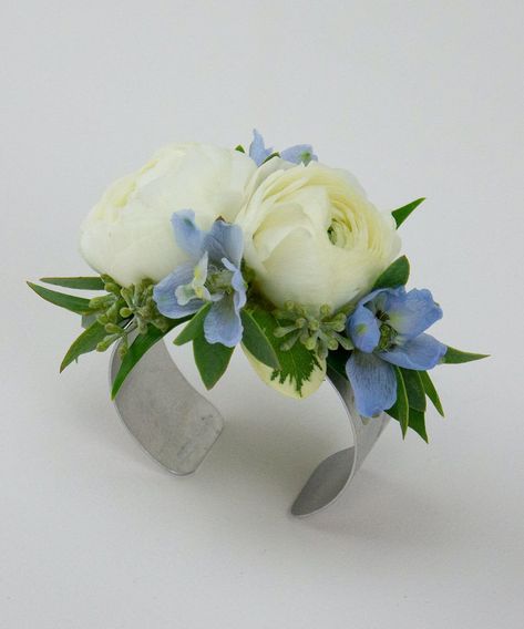 A dazzling corsage featuring two ranunculus blooms, accented with light blue delphinium. Light Blue Delphinium, How To Make Corsages, Ranunculus Centerpiece, Red Rose Boutonniere, Diy Wrist Corsage, Prom Flowers Corsage, Blue Corsage, Ranunculus Boutonniere, White Corsage