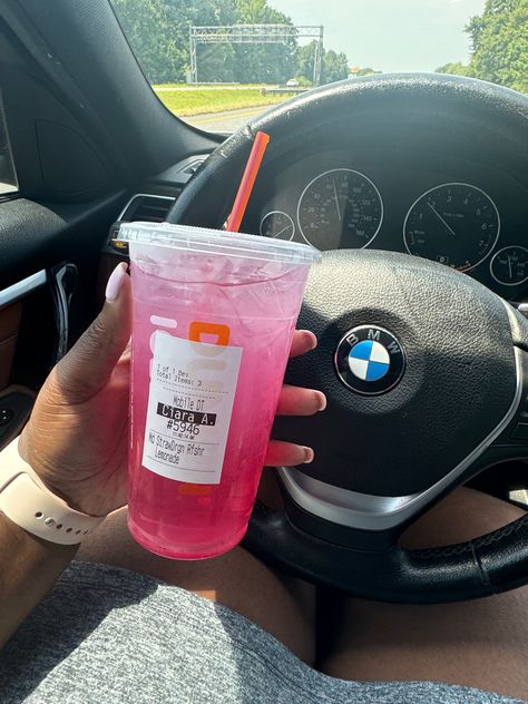 A hand holding a pink Dunkin’ Strawberry Refresher drink, with a highway visible through the car window. Dunkin Donuts Refreshers Recipe, Dunkin Donuts Drinks Refreshers, Dunkin Strawberry Refresher Recipe, Dunkin Raspberry Watermelon Refresher, Strawberry Refresher Dunkin, Healthy Dunkin Donuts Drinks, Strawberry Dragon Fruit Refresher Dunkin, Dunkin Aesthetic, Dunkin Drinks To Try