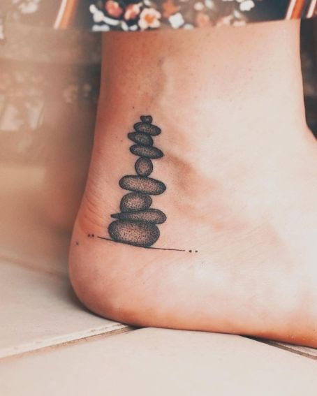 15 Beautiful Ankle Tattoos and Their Meanings You May Love to Try! Shin Ankle Tattoo, Zen Tattoos For Women, Mens Ankle Tattoos Ideas, Ebenezer Stone Tattoo, Tat Cover Up Ideas, Rock Cairn Tattoo, Petoskey Stone Tattoo, Cover Up Tattoo Ankle, Rocks Tattoo Stone