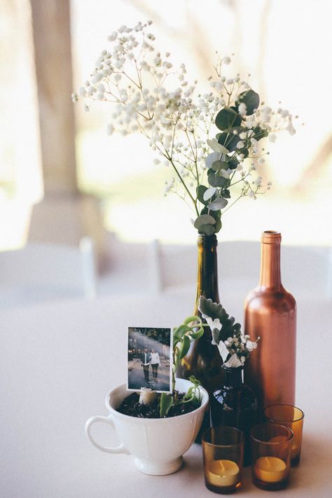 Wine Bottle Centerpieces Eucalyptus, Vintage Bottle Centerpieces, Wine Bottle With Flowers Centerpieces, Wine Bottle Flower Arrangements Wedding, Wine Bottle Table Decor, Picture Centerpiece Ideas, Wine Bottle Centerpieces For Wedding, Gold Wine Bottles, Wine Bottle Wedding Decor