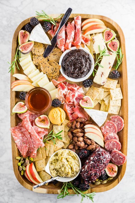 A wooden cheese board filled with cured meats, cheeses, apples, fig jam, berries and crackers. Harvest Charcuterie Board, Thanksgiving Charcuterie Board, Thanksgiving Charcuterie, Pecan Pie Bites, Plateau Charcuterie, Charcuterie Cheese, Charcuterie Platter, Board Charcuterie, Charcuterie And Cheese Board