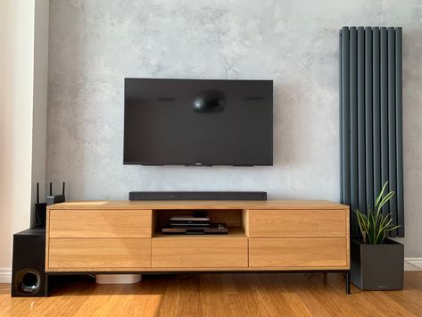 Loft living room idea with a concrete look wall. Solid oak tv unit on black metal legs. Anthracite vertical radiator. Radiator Tv Unit, Long Radiator, Tv Wall Stand, Tv Wall Idea, Decorating Tv Wall, Lounge Layout, Tv Wall Decoration, Wall Radiators, Solid Oak Tv Unit