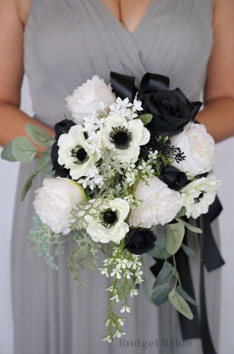 This striking waterfall brides’ bouquet is made with an elegant combination of ivory and black roses accented with anemones to create a beautiful amount of depth and contrast within this bouquet. The anemones and roses alongside the variety of mixed foliage and filler make this bouquet a stand out. As always, our bouquets are wonderful for those who are allergic to flowers and pollen, and have the added bonus of not attracting any bees or bugs. All of our waterfall bouquets are wired by hand, in Black Rose Flower Arrangements, Black And White Prom Flowers, Prom Flowers Bouquet Black Dress, Black And White Flower Bouquet, Black And White Wedding Flowers, Black And White Bouquet, Prom Flowers Bouquet, Black Wedding Flowers, Anemone Bouquet