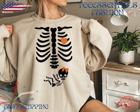 skeleton halloween maternity sweatshirt, funny pregnancy announcement sweat 2024, pregnant women costume, fall new mom sweater, mommy to be x trending fashion by teeessentials. Introducing our Cozy Comfort Sweatshirt, your new go-to for warmth and style! Crafted from ultra-soft, breathable fabric, this sweatshirt offers the perfect blend of comfort and durability. Its relaxed fit and ribbed cuffs ensure a snug wear, while the versatile design makes it easy to pair with any outfit—be it lounging at home or out on the town. Available in a range of trendy colors, it’s perfect for layering or wearing solo. Embrace effortless chicness and cozy up in this must-have #skeleton #shirt #women #trending fashion #halloween