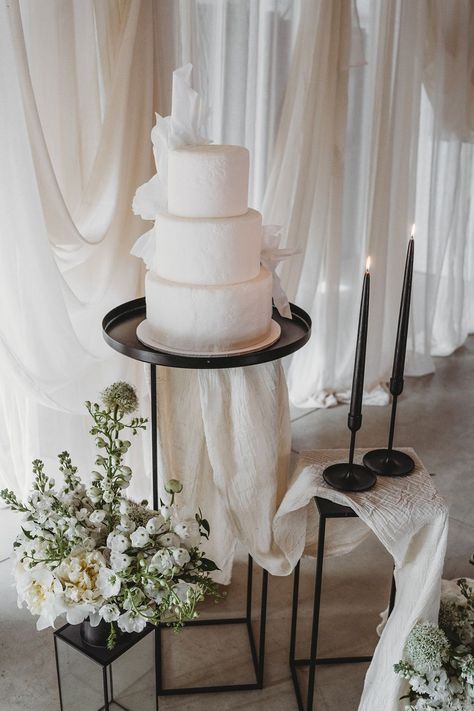 Three tier white iced vegan wedding cake with black taper candles and wedding drapes Wedding Cake Traditional, Wedding Cake Black And White, Wedding Cake Setup, Wedding Cake Black, Cake Black And White, Drapes Wedding, Wedding Cake Display Table, Wedding Drapes, Wedding Cake Table Decorations