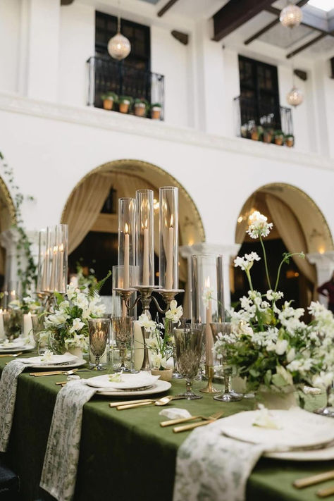 Elegantly draped in white foliage, each table shines under the glow of the candlelights | green tablescape wedding, green wedding table decor, moss green wedding table setting, green wedding aesthetic, minimalist wedding deco, green wedding centerpieces, white florals wedding reception, modern white wedding, all white wedding reception, classic wedding reception, classic white wedding, white flowers wedding decor, white flowers wedding, timeless wedding ceremony, classy wedding, white flowers Moss Green Wedding, Green Tablescape, Green Tablecloth, Green Themed Wedding, Green Wedding Colors, Cake Artist, Sage Green Wedding, Green Table, Venue Decor