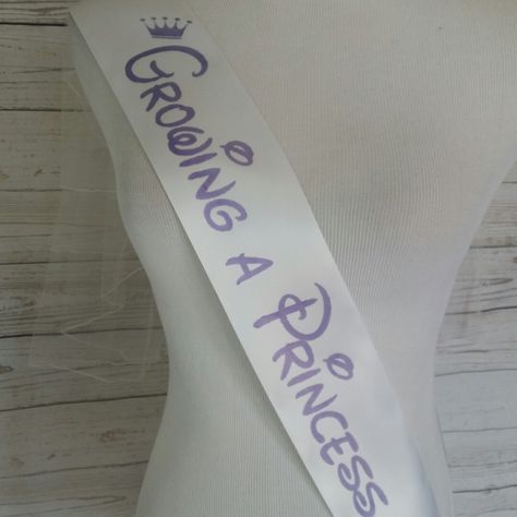 Growing a princess baby shower sash for mom to be to wear. White sash with purple lettering. Fast shipping. Order yours today. Baby Shower Sash For Mom, Purple Decorations, Baby Shower Sash, Baby Kicking, Pumping Moms, Baby Sleep Problems, Princess Baby, Third Baby, Baby Shower Princess