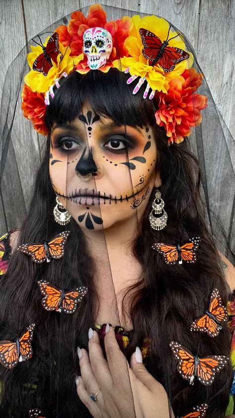 Brunette with butterflies in her hair wearing an orange and yellow marigold day of the dead flower crown with a sugar skull in the center and two skeleton hands below the flowers with monarchs on either side of the sugar skulls on the flowers Monarch Makeup Halloween, Sugar Skull Halloween Costume Diy, Butterfly Catrina Makeup, Skeleton Face Paint, Mexican Skeleton Costume, Sugar Skull Half Mask, Halloween Makeup Sugar Skull, Sugar Skull Costume, Skull Face Paint