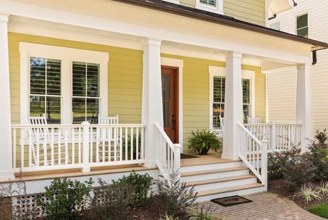 Close up shot of new yellow and white contemporary victorian style home in suburb. Porch spans front of home. Exterior Window Trim Ideas, Porch Column Wraps, Yellow House Exterior, White Porch, White Shutters, House Front Porch, Deck Colors, Porch Columns, Window Trim Exterior