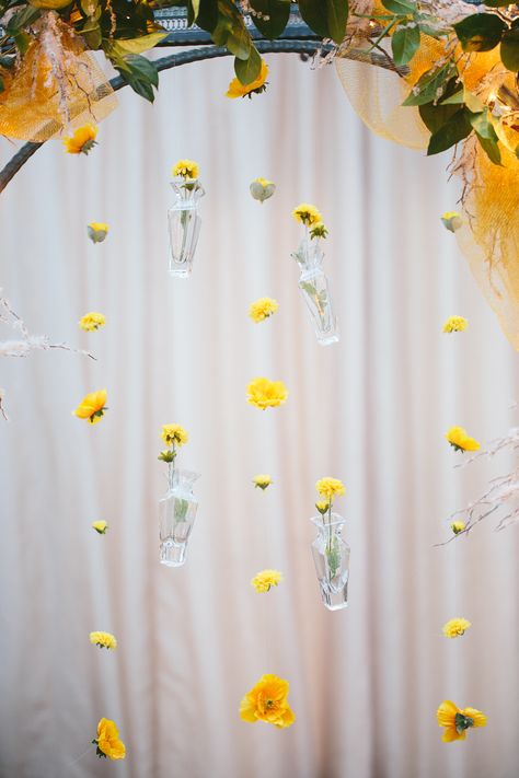 hanging vases with yellow flowers for wedding line backdrop. hung with fishing wire. Fishing Line Flower Backdrop, Bride To Bee Photo Backdrop, Fishing Line Flower Garland, Yellow Hanging Flowers, Hanging Wildflower Backdrop, Backyard Bbq Party, Hanging Vases, Yellow Wedding Flowers, Wedding Vases