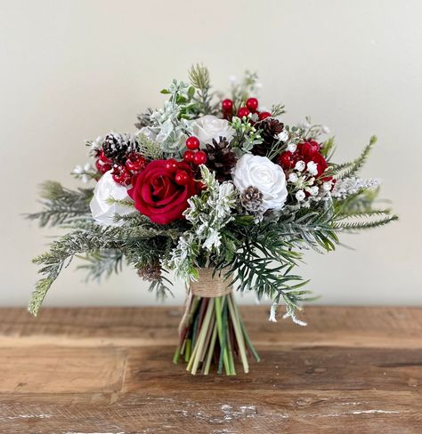 "DETAILS & SIZE  ---------------------------------------------------------- ❤ This classic  winter snow covered wedding bouquet is put together with high quality red and white silk flowers, red berries, babies breath, pinecones, eucalyptus and all sorts of different evergreens. The handle is also wrapped with twine and finished with a twine bow to give it a beautiful rustic touch. This bouquet is perfect for a wedding in winter or around Christmas. Available in 5 different sizes. The 12\" brides bouquet is photographed in the listings Before you choose the size of bouquet that you like, I would highly recommend that you measure the size against yourself to make sure that you choose the perfect size for you.  MATCHING BOUQUET: https://www.etsy.com/ca/listing/1572923381/red-wedding-bouquet-r Red White Green Wedding Flowers, Christmas Wedding Ring Bearer, Outdoor Christmas Wedding Ideas, Wedding Flowers Christmas, Bridesmaid Bouquet Christmas, Christmas Wedding Buttonholes, Christmas Wedding Centrepiece Ideas, Cheap Christmas Wedding Ideas, Christmas Bridal Bouquet Winter Bride