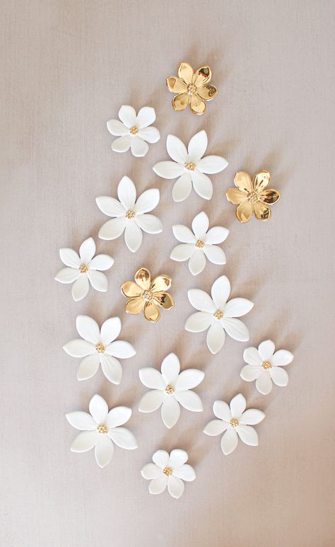 A little variation on our white decor!  We offer 15 ceramic flowers for wall decoration.  The color is a shiny white and a center of 24k gold mini beads.  We added 3 small all-gold flowers for a bright touch.  Breakdown:  6 flowers around 8cm  (3.14 in.)  3 flowers around 7cm (2.75 in.)  3 flowers around 6 cm (2.36 in.)  3 flowers around 6cm all gold ( 2.36in)  To hang them on the wall or on your panel, there are 2 small loops at the back. Please consider any customs fees  Feel free to reach out if you have any questions.  All our flowers are handmade in our studio.  o¨o¨o¨o¨o¨o¨o¨o¨o¨o For further informations concerning shipping and packing : https://www.etsy.com/fr/shop/LysaCreationDesign/policy#seller-info?ref=shopinfo_seller_information_leftnav Flowers For Wall, Ceramic Star, Flowers For Home, Kids Bedroom Walls, Ceramic Wall Decor, Ceramic Wall Art, Clay Wall, Playroom Wall Art, Gold Ceramic