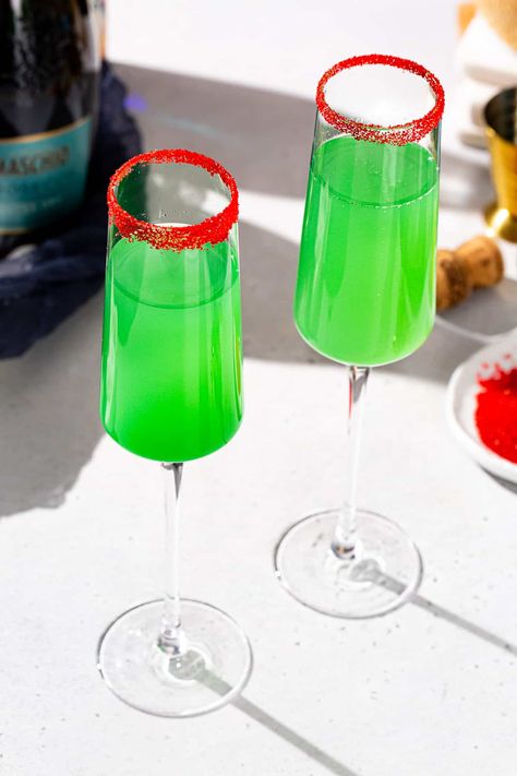 This Grinch Mimosa cocktail is an easy and festive champagne cocktail for Christmas! This fizzy green drink with a red sugar rim is perfect for the holiday season. This drink features pineapple juice instead of orange juice, and a touch of Blue Curaçao liqueur to give it a vibrant green color and a little extra flavor. Perfect for your Christmas cocktail menu! Grinch Drink For Adults, Grinch Mimosa, Poinsettia Cocktail, Grinch Drink, Easy Drinks To Make, Blue Curacao Liqueur, Classic Eggnog, Mimosa Cocktail, Melon Liqueur