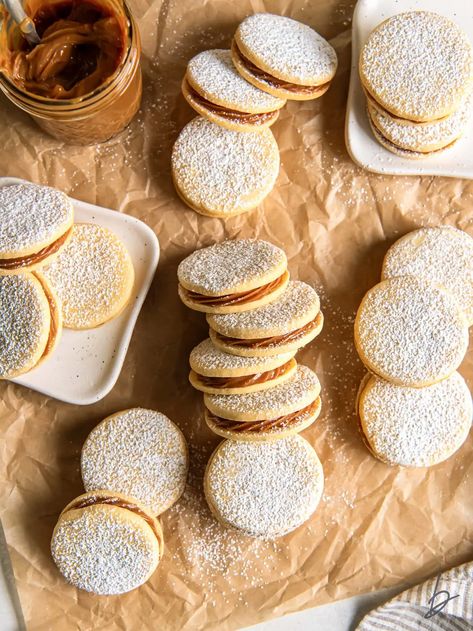 dulce de leche sandwich cookies (alfajores) dusted with powdered sugar on parchment paper. Christmas Alfajores, Alfajores Recipe Argentina, Easy Alfajores Recipe, Alfajores Recipe, Piped Cookies, Powdered Sugar Cookies, Mexican Cookies, Unique Recipe, Buttery Shortbread Cookies