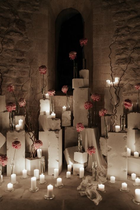 Elodie Villemus used 450 candles to create the perfect contrast against the ancient stones of the chapel. This also helped create the perfect ceremony space featuring white votives surrounding concrete blocks adorned with single stem vases. Pink was the perfect floral color choice to help create a pop of soft color against the stones. Candle Wedding Ceremony Altars, Candle Entrance, Negative Space Wedding, Candle Installation, Ceremony Space Decor, Rose Ceremony, Aisle Candles, Stone Structures, Installation Ideas