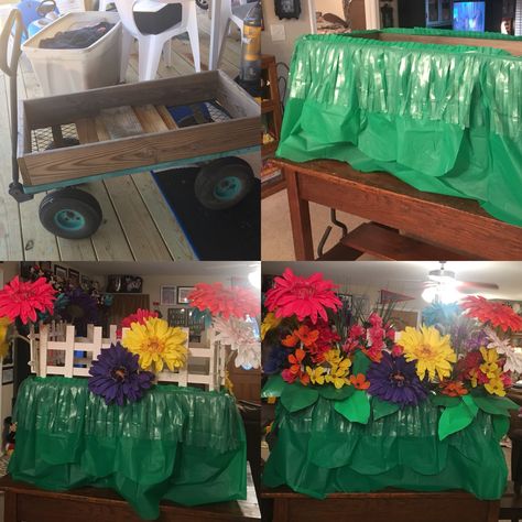 I took this simple, rugged wagon and turned it into a beautiful flower garden float for my little girls Preschool Mardi Gras parade. The green on the bottom is a table skirt ruffle that came with adhesive so it was super easy to attach. The white picket fencing came from Lowes, and I screwed it into the wood rails that was on the frame of the wagon. All the flowers were attached with white zip ties. And for the leaves, I cut leaf shapes out of light green and darker green paper plates. The stiff Wagon Decorations For Parade, Easy Parade Float Ideas, Wagon Parade Float Ideas Kids, Garden Parade Float Ideas, Garden Float Parade, Flower Float Parade, Wagon Mardi Gras Float For Kids, Wagon Floats, Parade Float Supplies Walmart