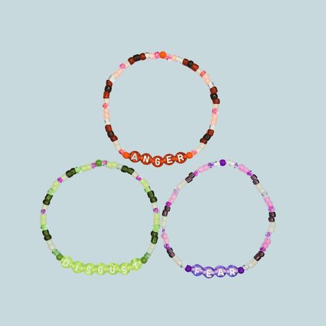 Three colourful beaded bracelets on a light blue background, each with letter beads spelling out different emotions: ANGER on a red and white bracelet, DISGUST on a green and white bracelet, and FEAR on a purple and white bracelet. Fear Inside Out, Themed Bracelets, Bracelet Trio, Bold Accessories, Themed Jewelry, Bracelet Beaded, Bracelet Set, Arm Band, Beaded Bracelet