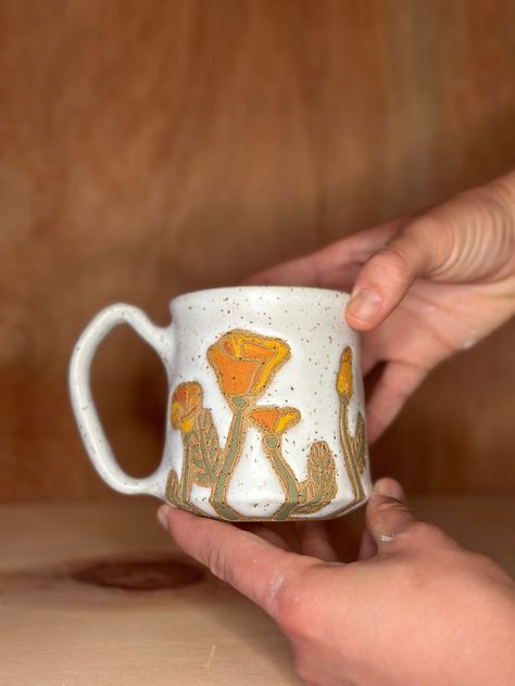 Sweet california poppy mug featuring 8 poppies on speckled clay. Hand thrown, trimmed, painted and carved.  I use a combination of underglazes, engobes, and oxides and glaze to produce desired effects. If you've ever done ceramics you understand the practice has lengthy and time consuming processes and techniques. These works take anywhere from 4-6 weeks from start to finish. Underglaze Carving, Underglaze Ideas, Sweet California, Pottery Patterns, Glaze Ideas, Pottery Inspo, Handmade Mugs, Speckled Clay, Clay Hand