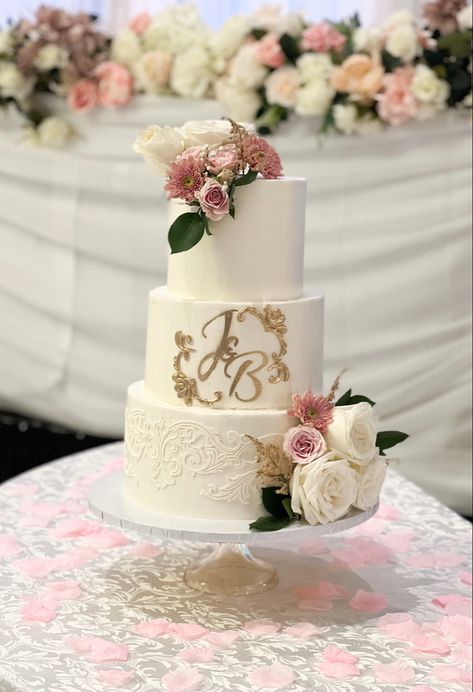 Three tier cake with pink and white florals. Subtle lace patterns. In the middle it reads “J & B” in gold Dusty Rose Wedding Cake, Wedding Cake 3 Tier, Cake 3 Tier, Rose Wedding Cake, Rose Gold Wedding Cakes, Cake Floral, Rose Gold Theme, Small Wedding Cakes, Mauve Wedding